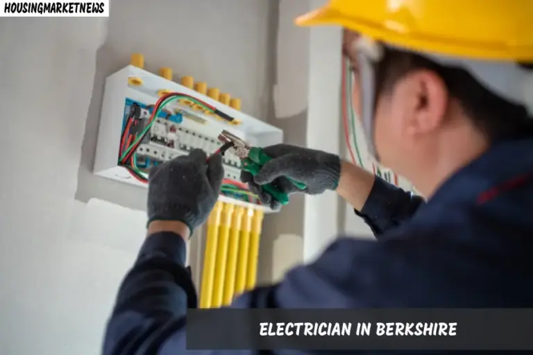 A man wearing a hard hat and gloves is engaged in electrical work on a panel, showcasing his skills in Berkshire.