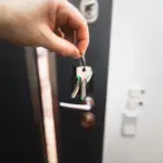 A hand holding house keys in front of a front door